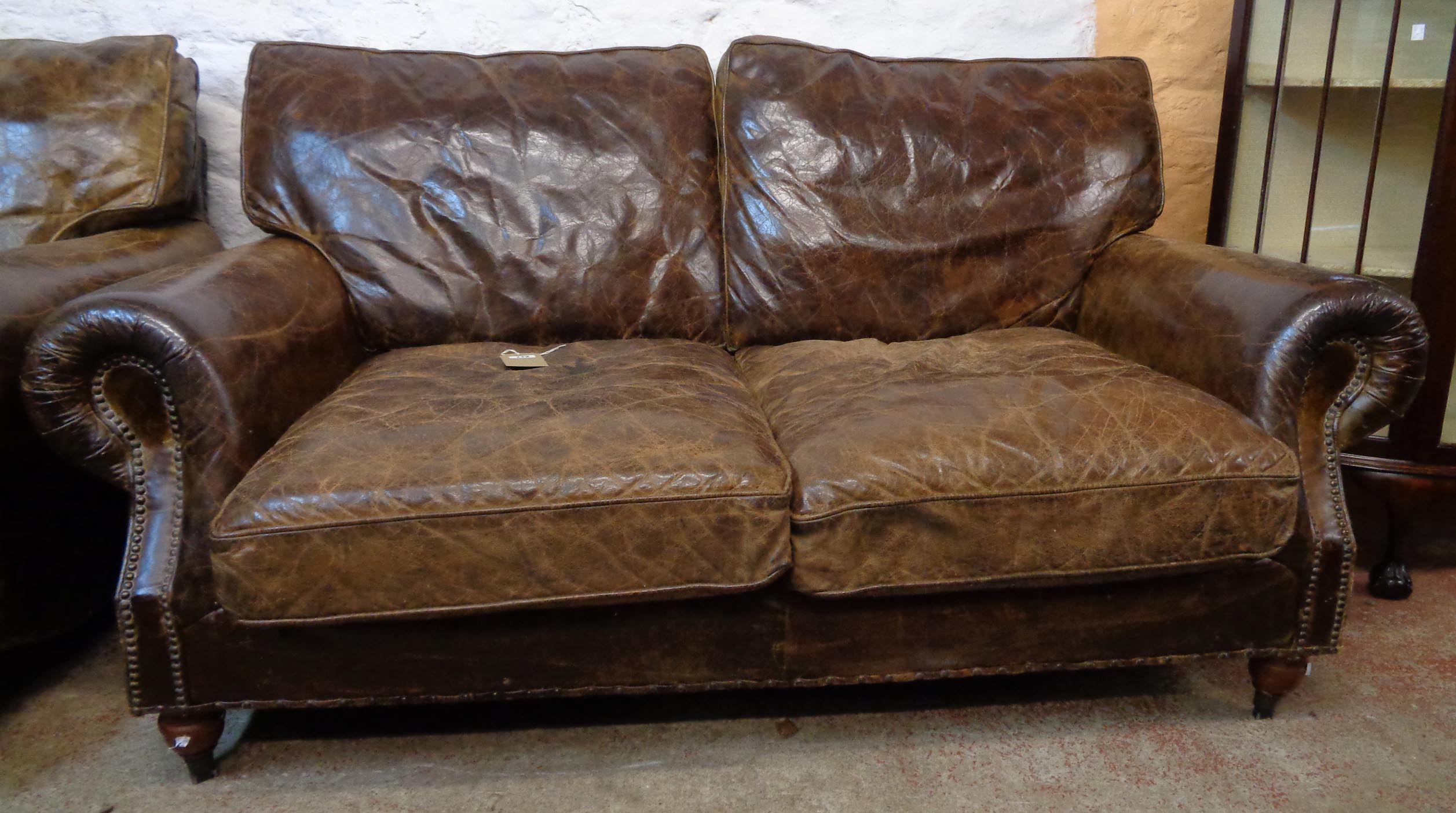 A 5' 8" studded brown leather upholstered two seater settee and armchair to match - the settee