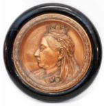 A circular copper plaque depicting Queen Victoria, in ebonised frame