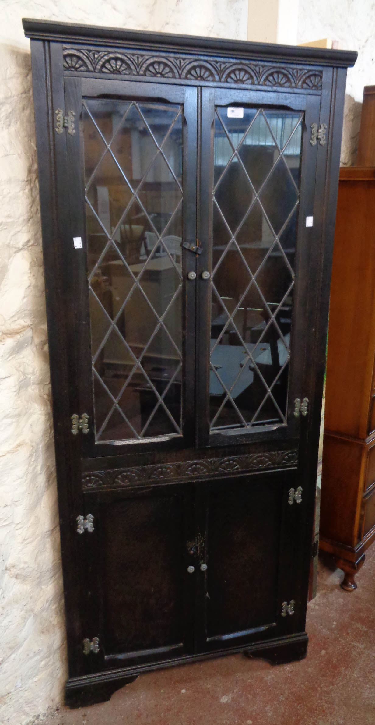 A 30" 20th Century stained wood corner cabinet in the antique style with leaded glazed panel doors