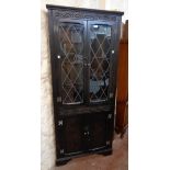 A 30" 20th Century stained wood corner cabinet in the antique style with leaded glazed panel doors