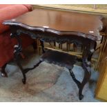 A 28 1/2" Edwardian stained walnut two-tier occasional table with serpentine surfaces and carved