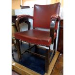 A mid 20th Century stained oak framed panel back elbow chair with studded red leatherette