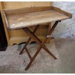 An old stained wood butler's tray, set on folding stand