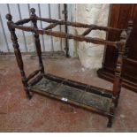 An early 20th Century stained wood stick stand with decorative moulded supports and metal drip-tray