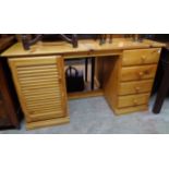 A 4' 5" modern polished pine kneehole desk with louvered cupboard door to one side and flight of