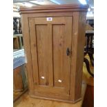 A 21" old waxed pine wall hanging corner cabinet with panelled door and canted sides