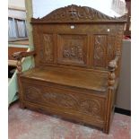 A 4' 1 1/2" polished carved oak settle bench with green man top rail, central interior scene,