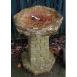 A 24" concrete bird bath, set on a brick effect pedestal base