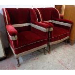 A pair of Edwardian box framed armchairs upholstered in tasselled and studded red velour, set on