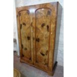 A 4' 4" Victorian figured walnut double wardrobe with pair of arched panel doors enclosing four