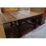 A 1930's polished oak draw-leaf dining table, set on antique style base with bulbous turned supports