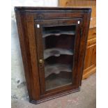 A 28" late Georgian oak wall hanging corner cabinet with three scalloped shelves enclosed by a