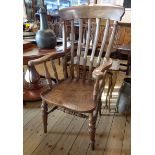 An old polished wood high lath back elbow chair with moulded solid elm seat, set on turned supports