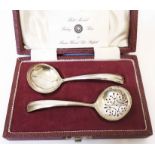 A case containing Francis Howard silver ladle and sifter spoon