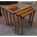 A nest of three 1970's teak tea tables, the largest with part tile inset top