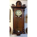 A walnut cased Vienna style regulator wall clock with decorative dial, visible pendulum, mask