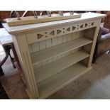 A 3' 11" painted wood three shelf open bookcase with pierced frieze, flanking fluted decoration