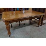 A late Victorian polished quarter sawn oak dining table, set on heavy turned and reeded legs with