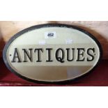 A cast iron oval "Antiques" sign