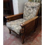 A 1930's stained oak framed reclining armchair with original button back upholstery and turned