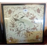 A framed early 20th Century silk embroidery panel depicting a peacock and scrolls - faded