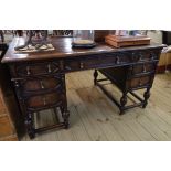 A 4' 6" early 20th Century stained oak kneehole desk by Gill & Reigate with brown leather inset top,