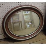 An oval wall mirror with part painted frame