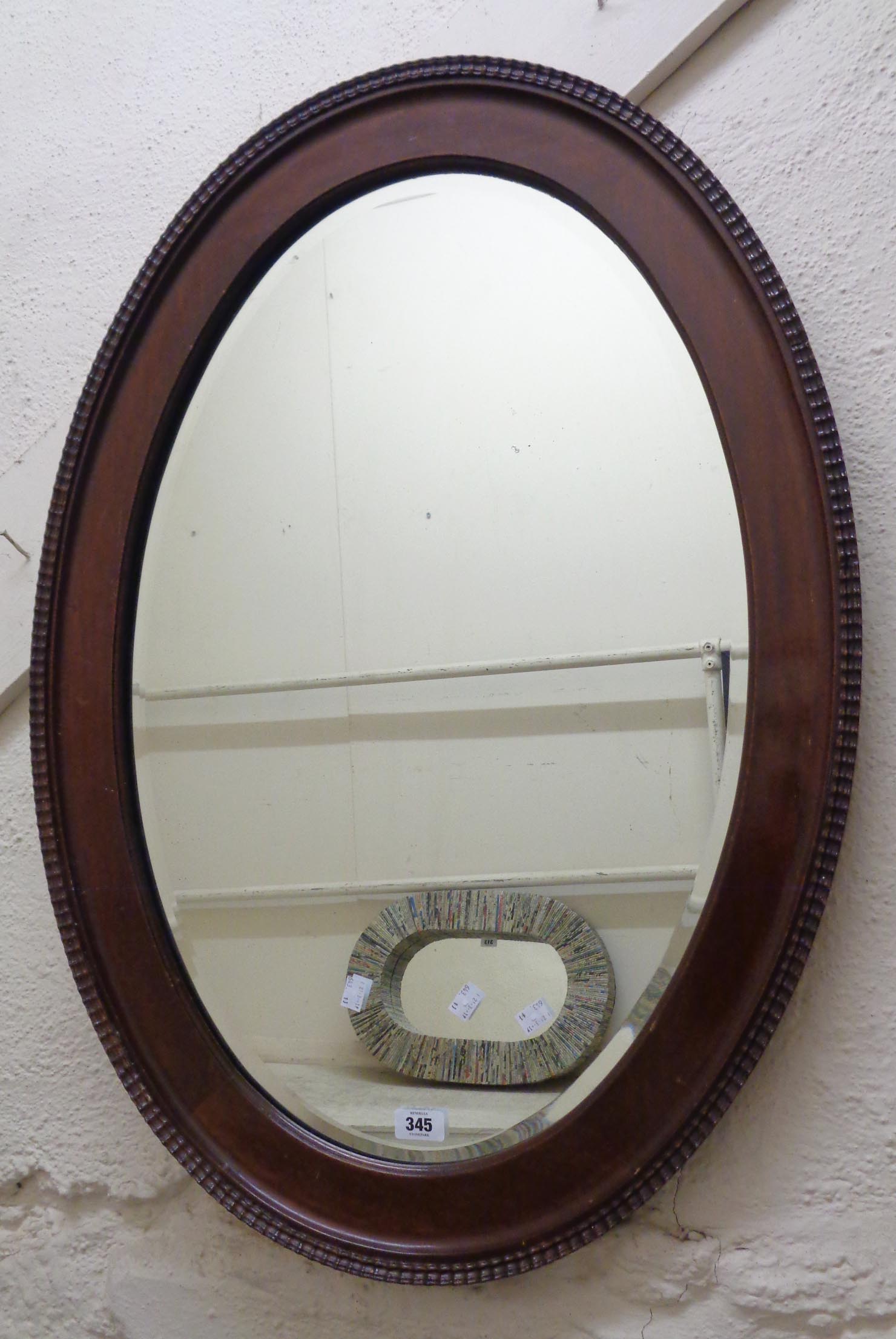 An early 20th Century moulded walnut framed bevelled oval wall mirror