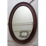 An early 20th Century moulded walnut framed bevelled oval wall mirror