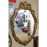 An ornate gilt plaster framed oval wall mirror