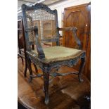 A 19th Century carved walnut framed elbow chair with decorative top rail, rattan back and remains of