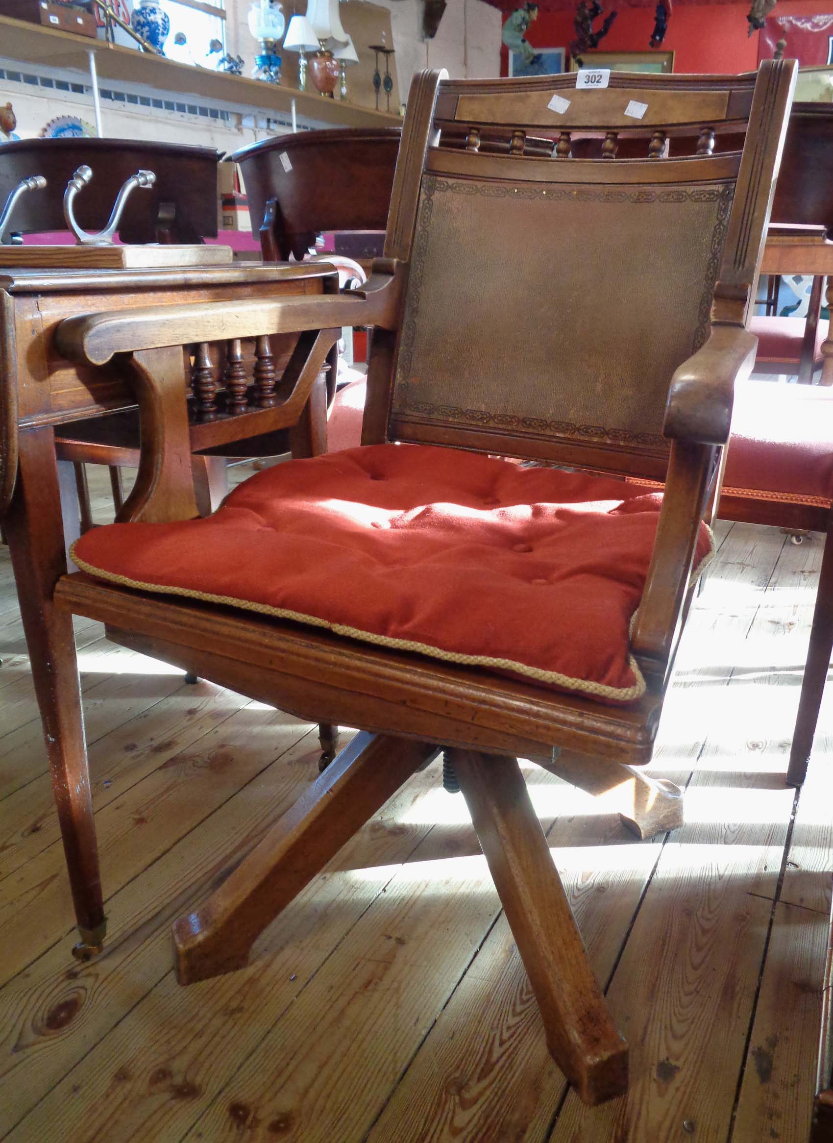 An Edwardian stained oak framed swivel office elbow chair with tooled fibreboard back and seat panel