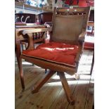 An Edwardian stained oak framed swivel office elbow chair with tooled fibreboard back and seat panel