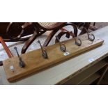 A 30 1/4" stained wood wall mounted coat rack with five cast metal hooks