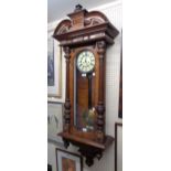 A walnut cased Vienna style regulator wall clock with decorative dial, visible pendulum, ornate