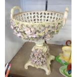 A continental ceramic basket pattern centrepiece with pierced and profuse floral decoration, crossed