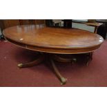 A 4' 1 1/2" reproduction mahogany cross banded and strung oval coffee table, set on turned pillar