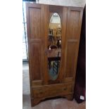 An Edwardian inlaid mahogany single wardrobe with bevelled oval mirror panel door and drawer under -