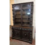 A 4' 5 1/2" Victorian heavily carved stained oak two part cabinet with associated tongue moulding to