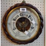 An antique stained oak rope twist bordered aneroid wall barometer with visible works to dial