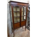 A 36" Edwardian walnut display cabinet with material lined interior enclosed by a pair of part