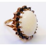A hallmarked 375 gold dress ring, set with large central milky opal within a sapphire encrusted