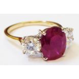 A hallmarked 750 gold ring, set with central oval ruby flanked by two brilliant cut diamonds -