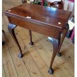 A 24" early 20th Century figured mahogany fold-over card table, set on acanthus carved cabriole legs