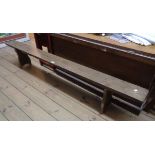 A 6' 5" old stained pine form bench, set on shaped standard ends