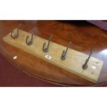 A 30 1/2" stained wood wall mounted coat rack with five cast iron hooks