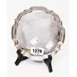 A 6" diameter silver salver with shaped rim and scroll feet