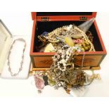 A decorative wooden box containing a quantity of assorted costume jewellery