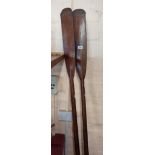 A vintage pair of stained wood sweep oars with leather grips