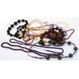 A bag containing assorted necklaces including Italian glass beads, polished hardstones, etc.